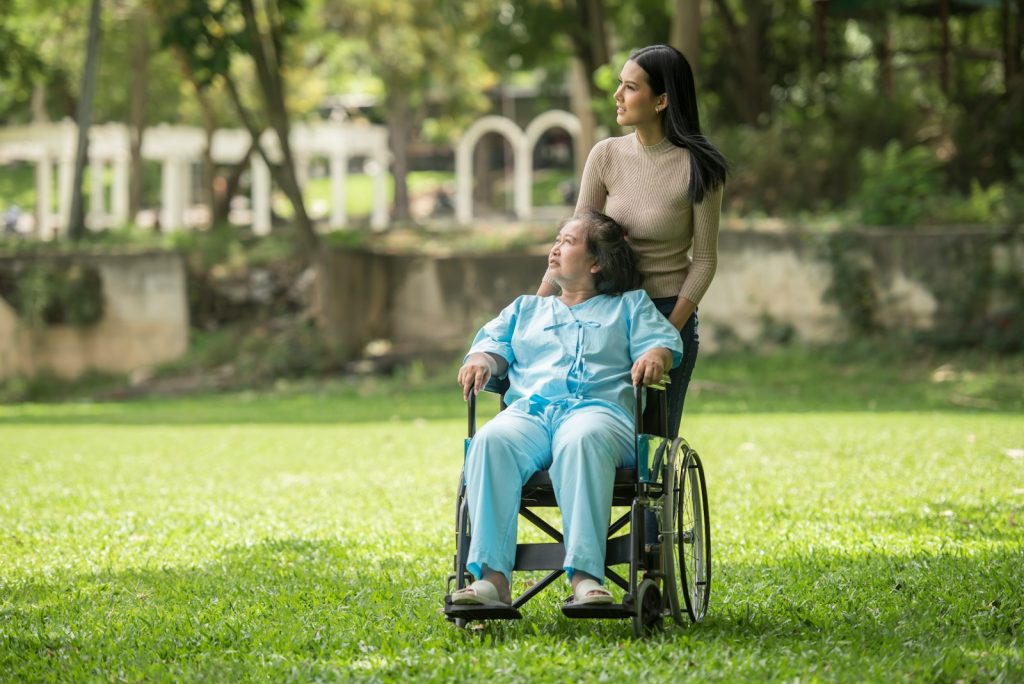 A woman in a wheelchair standing next to a man in a park
